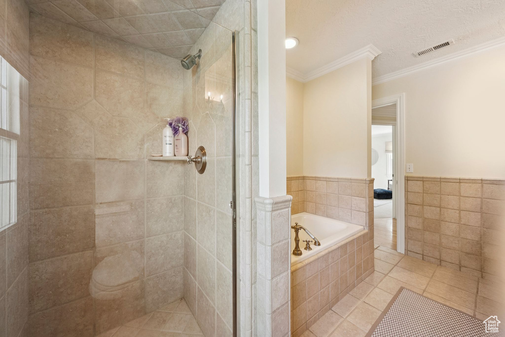 Bathroom featuring ornamental molding, a shower stall, a bath, tile patterned flooring, and tile walls