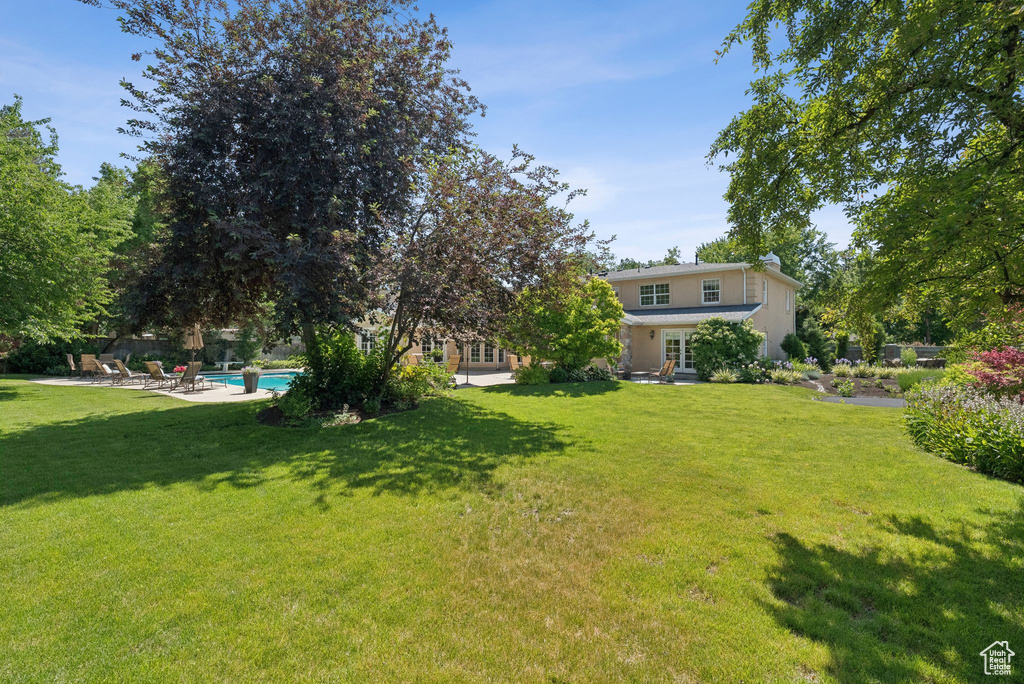 View of green lawn with french doors, an outdoor pool, and a patio