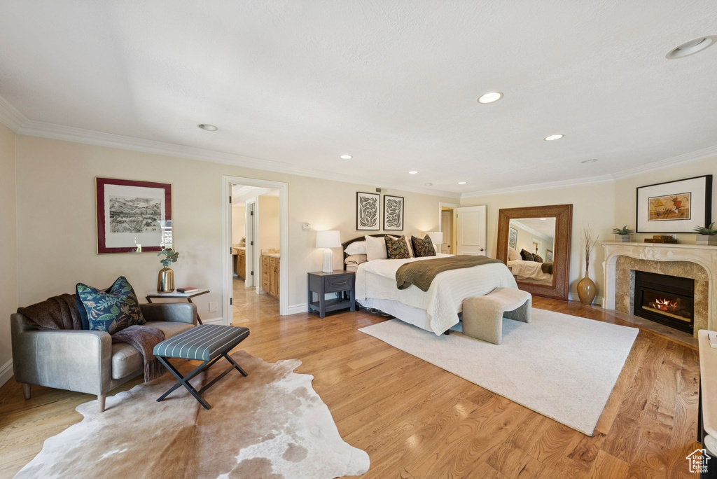 Bedroom with light wood-style flooring, a fireplace, crown molding, recessed lighting, and baseboards