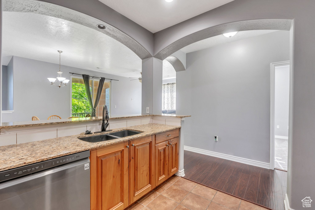 Kitchen featuring dishwasher, a sink, arched walkways, and light stone countertops