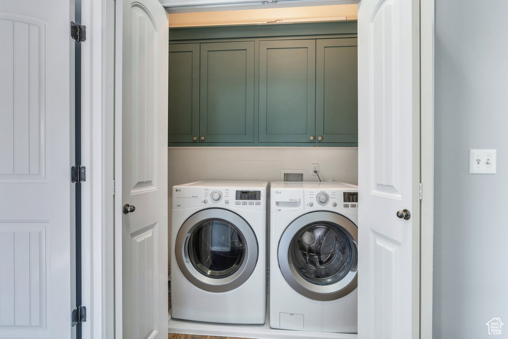 Washroom featuring separate washer and dryer and cabinet space