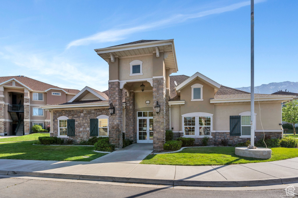 View of front facade featuring stucco siding, stone siding, and a front lawn