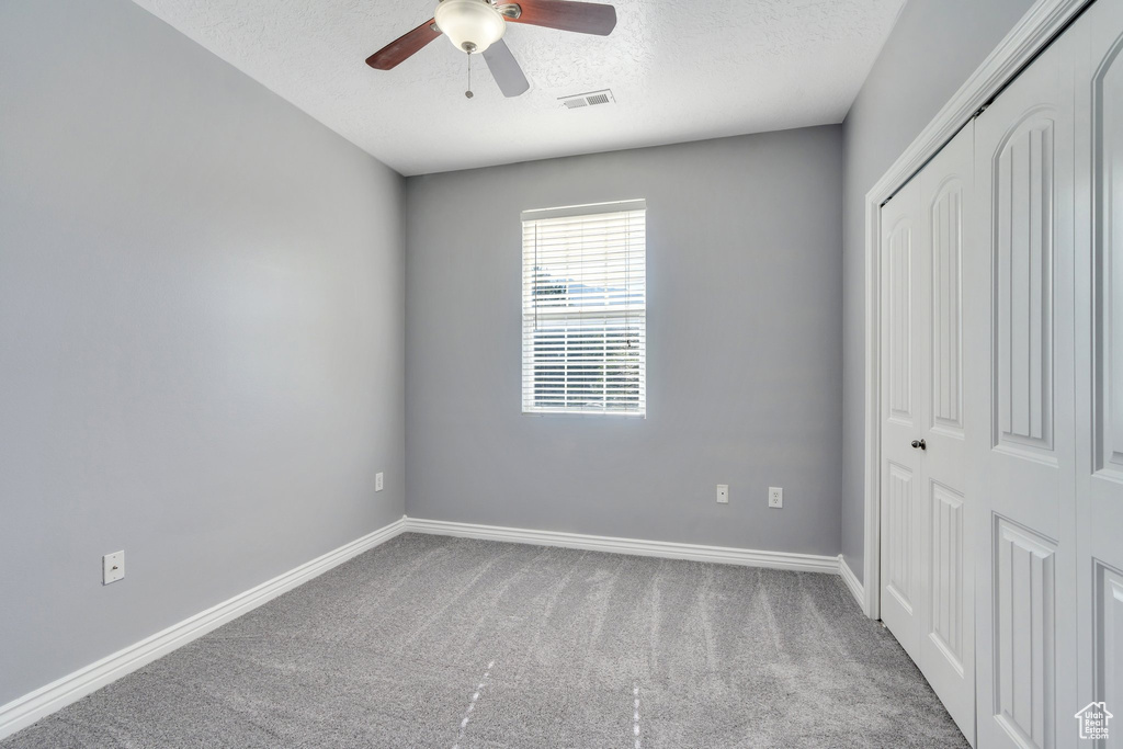 Unfurnished bedroom with a closet, carpet flooring, a textured ceiling, baseboards, and ceiling fan