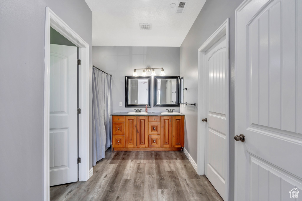 Bathroom with double vanity, wood finished floors, and a shower with curtain