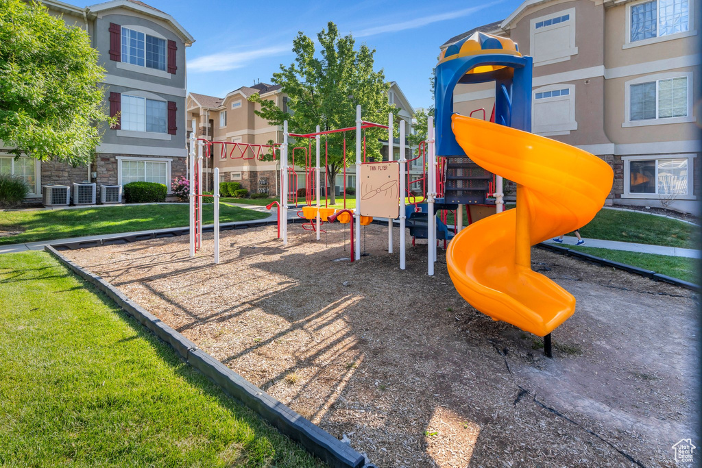 Community play area with central AC unit, a yard, and a residential view