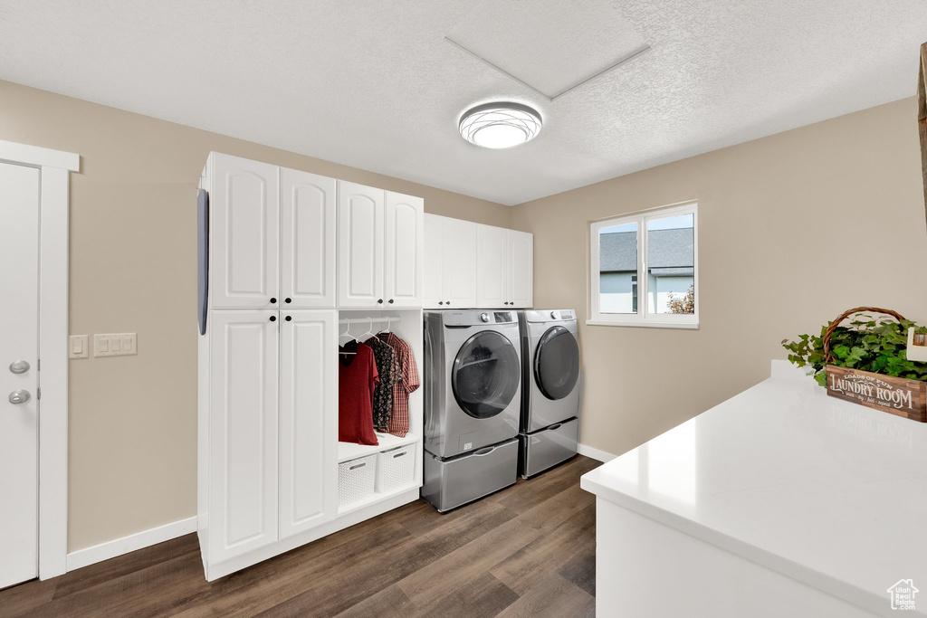 Laundry area with separate washer and dryer, dark wood finished floors, baseboards, cabinet space, and a textured ceiling
