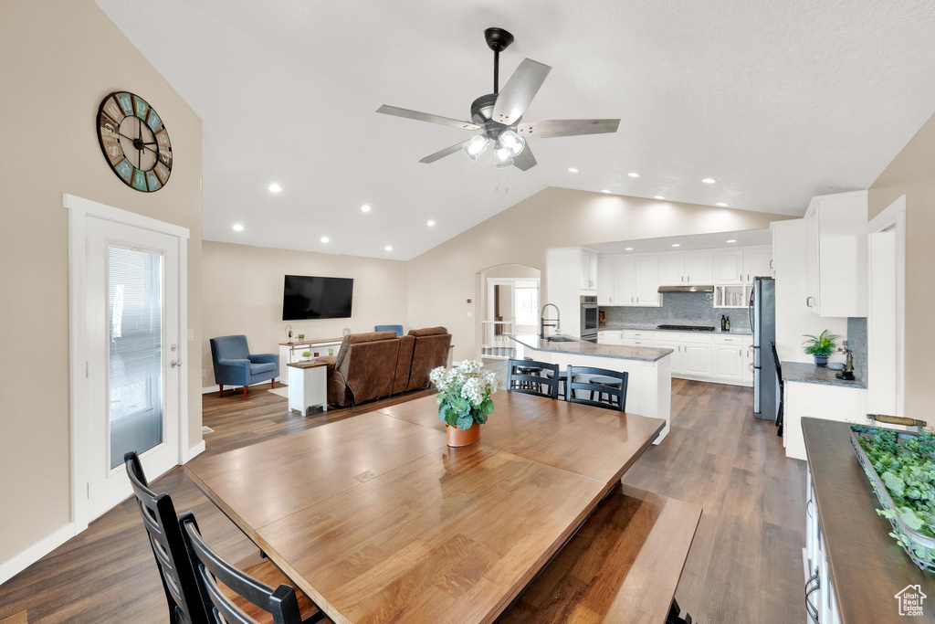 Dining area featuring ceiling fan, arched walkways, dark wood-type flooring, recessed lighting, and high vaulted ceiling