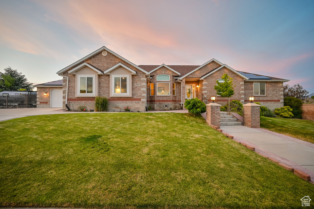 View of front of property with brick siding, roof mounted solar panels, and driveway