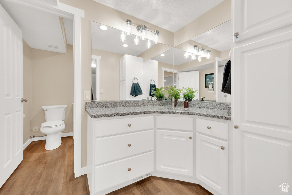 Bathroom featuring vanity, wood finished floors, toilet, and baseboards