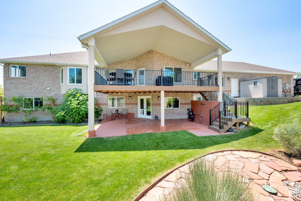 Back of house with brick siding, a patio, a yard, french doors, and stairs