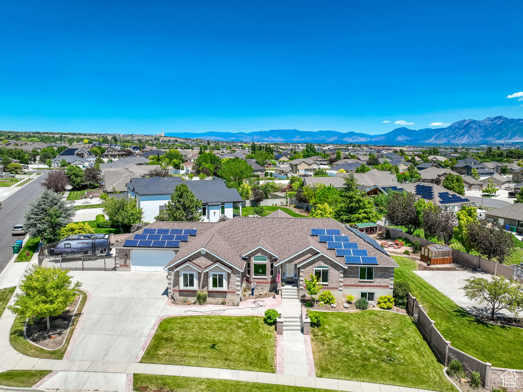 View of front of house with driveway, a residential view, solar panels, a mountain view, and a garage