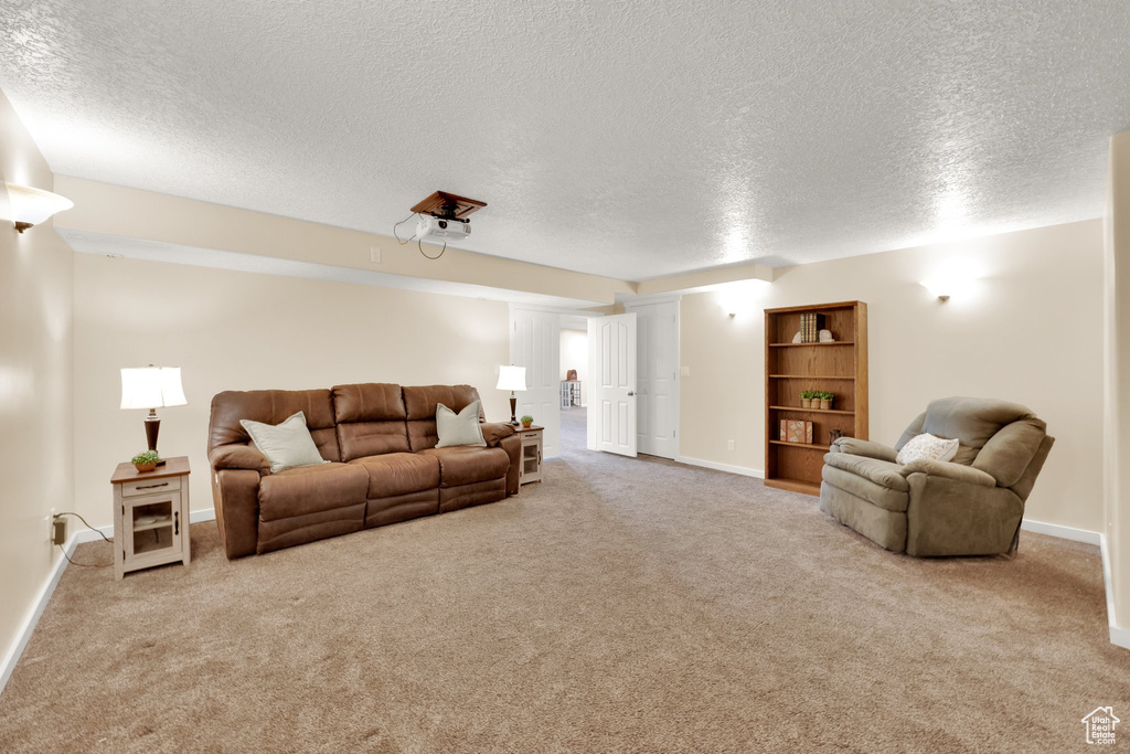 Carpeted living area featuring a textured ceiling and baseboards