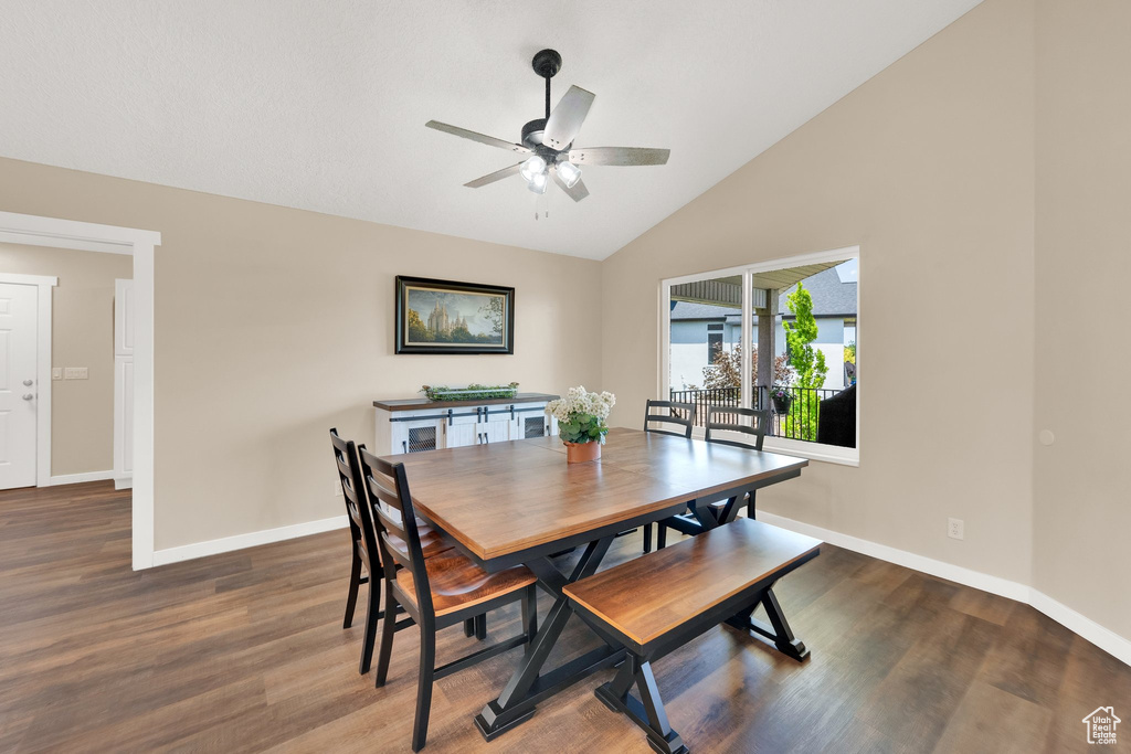 Dining space with a ceiling fan, wood finished floors, baseboards, and high vaulted ceiling