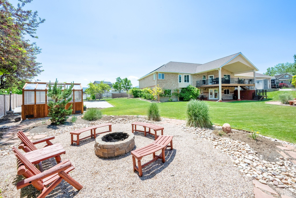 View of patio / terrace featuring a fire pit, a greenhouse, an outbuilding, and a balcony