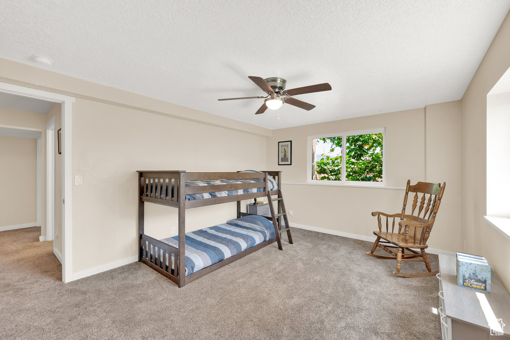 Bedroom with carpet, baseboards, a textured ceiling, and ceiling fan