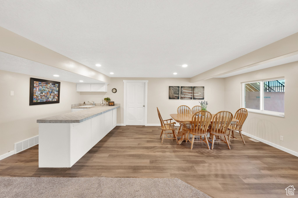 Dining space with recessed lighting, baseboards, wood finished floors, and bar with sink