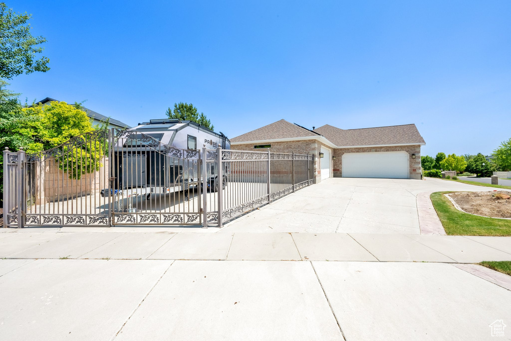 View of front of property featuring driveway, an attached garage, a fenced front yard, a gate, and brick siding