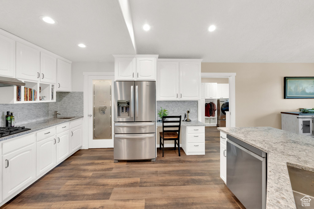 Kitchen featuring stainless steel appliances, a sink, washer and clothes dryer, decorative backsplash, and white cabinets