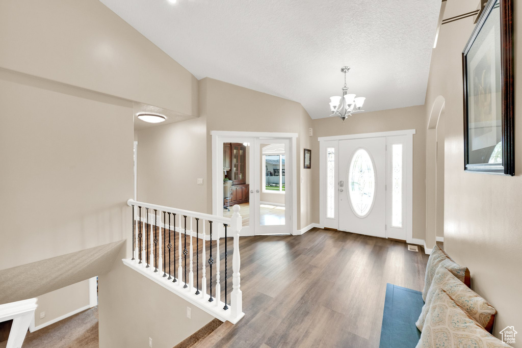 Entryway featuring lofted ceiling, a chandelier, dark wood finished floors, and baseboards