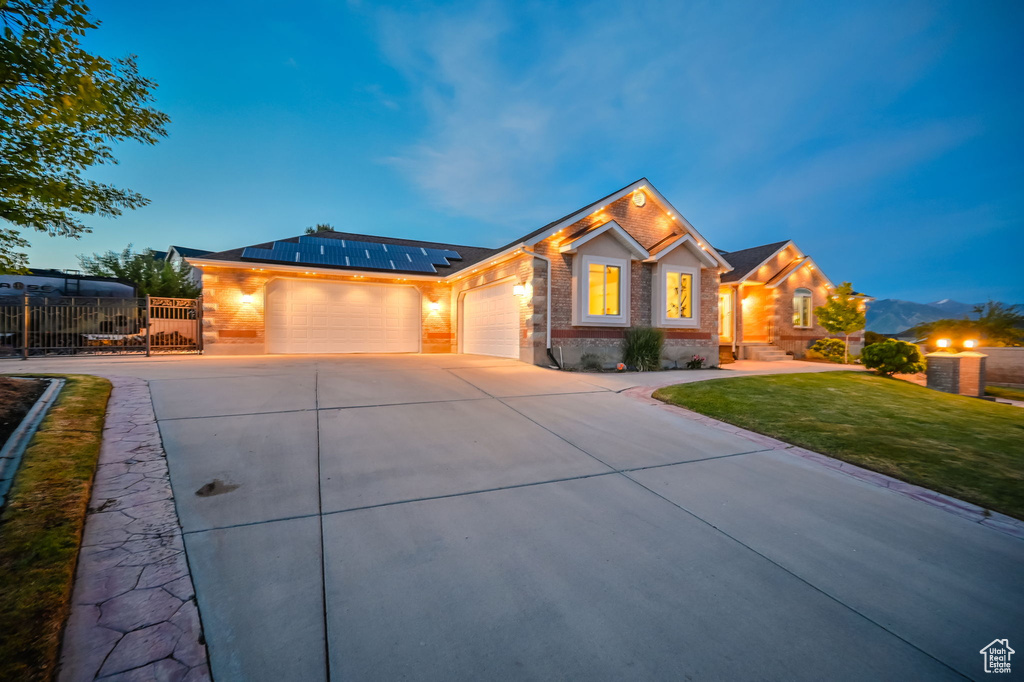 Ranch-style house with an attached garage, concrete driveway, solar panels, and brick siding