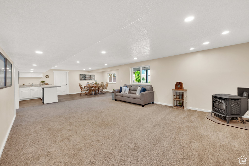 Living area with carpet, recessed lighting, baseboards, and a wood stove