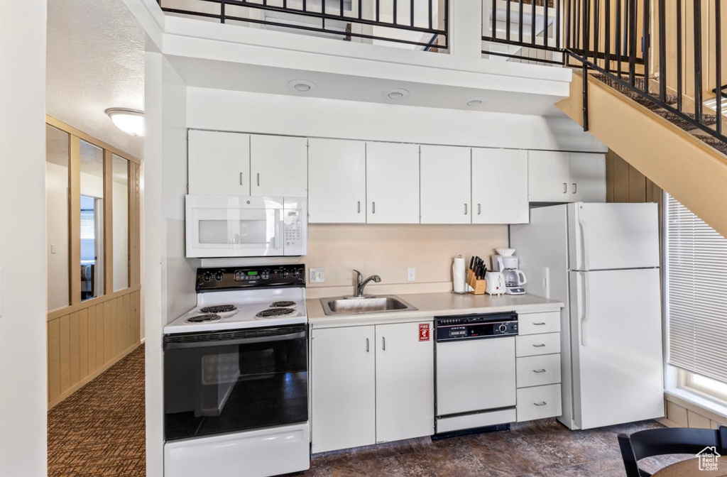 Kitchen featuring white appliances, a sink, light countertops, and white cabinets