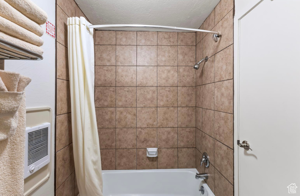 Bathroom featuring shower / tub combo and a textured ceiling