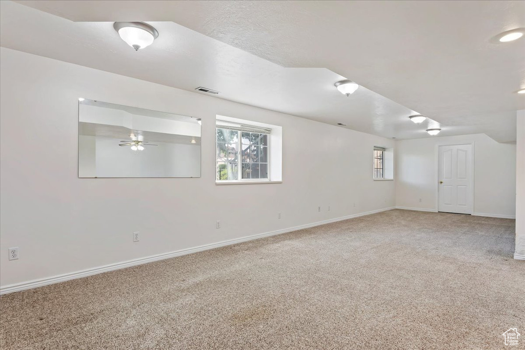 Unfurnished room featuring light carpet, baseboards, plenty of natural light, and ceiling fan