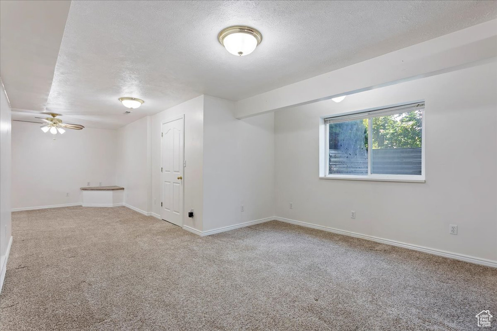 Spare room with a textured ceiling, carpet, baseboards, and a ceiling fan