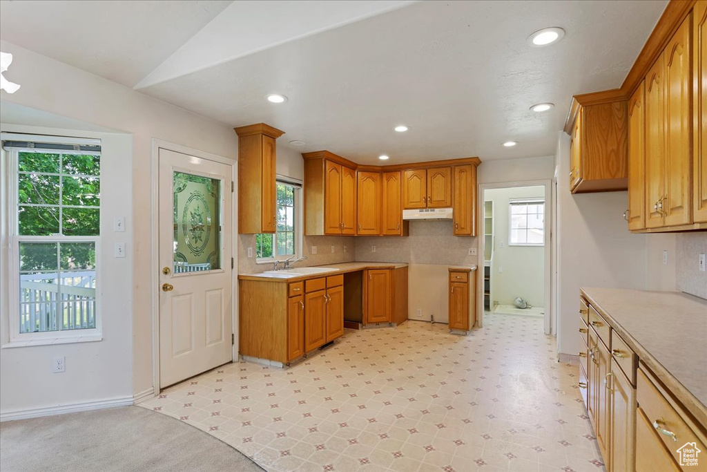 Kitchen featuring plenty of natural light, under cabinet range hood, brown cabinets, and recessed lighting