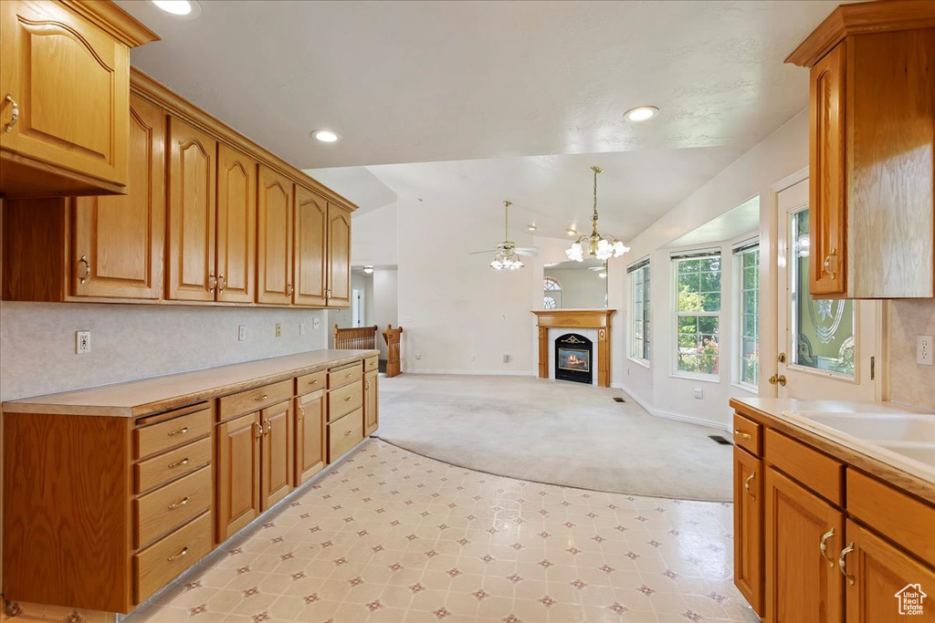 Kitchen with light carpet, a ceiling fan, a glass covered fireplace, light countertops, and baseboards