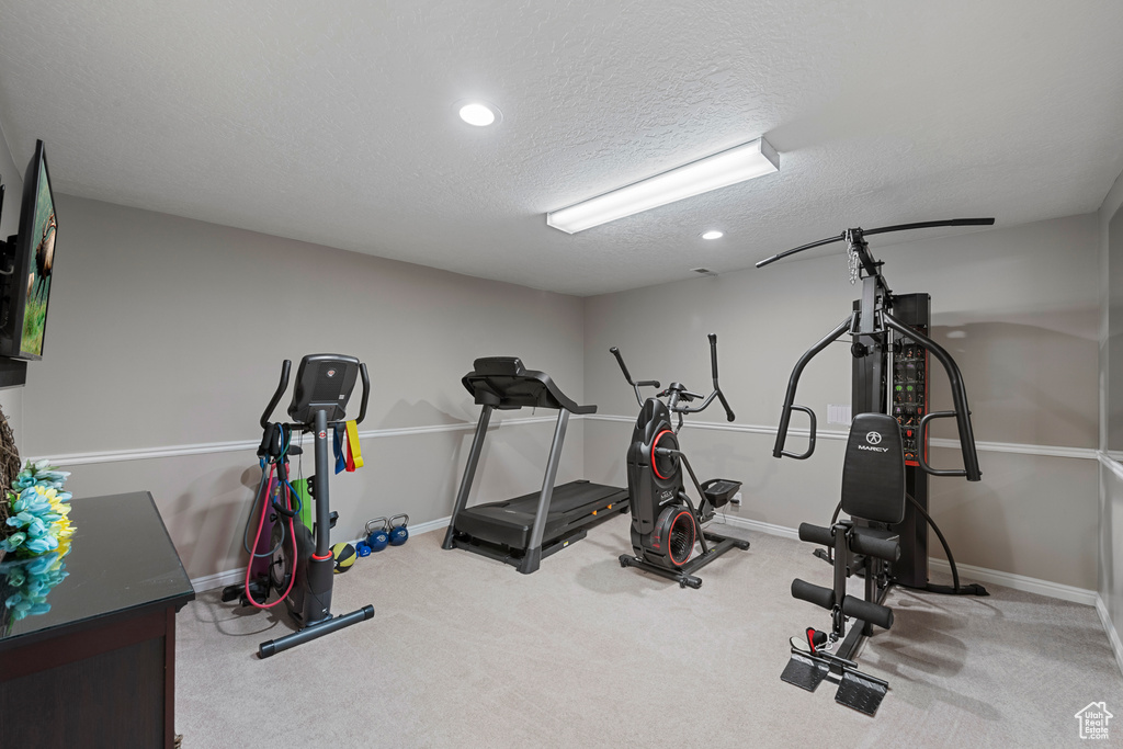 Exercise area featuring carpet, baseboards, a textured ceiling, and recessed lighting