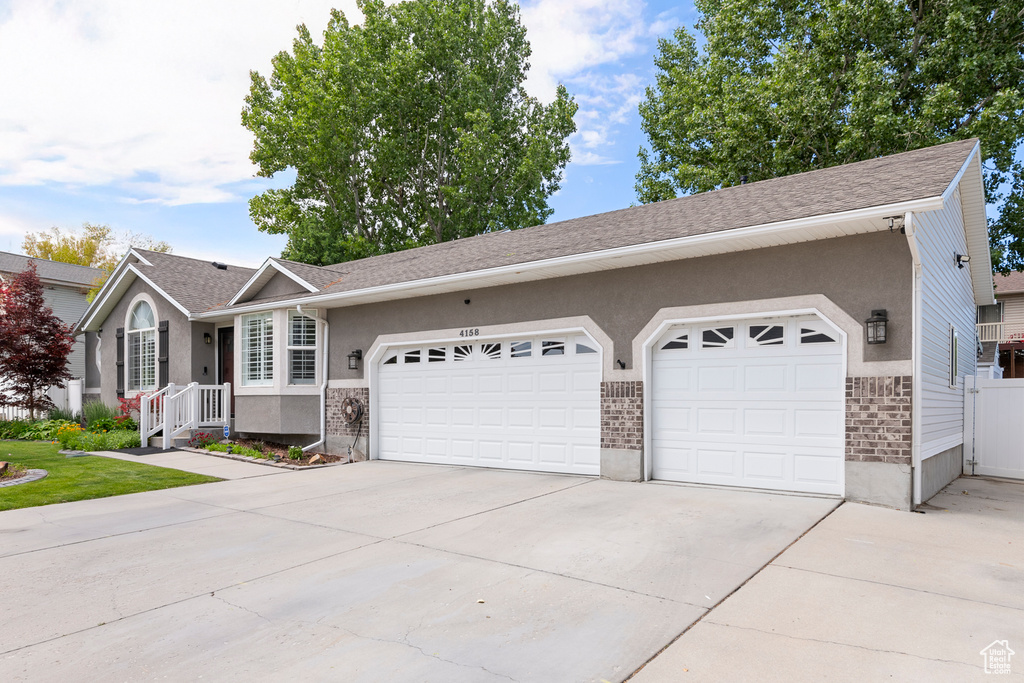 Ranch-style house featuring a garage, concrete driveway, stucco siding, and brick siding
