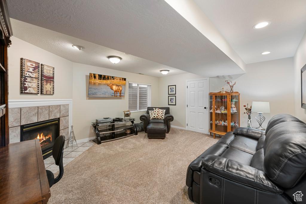 Living area featuring light colored carpet, baseboards, a tile fireplace, and recessed lighting