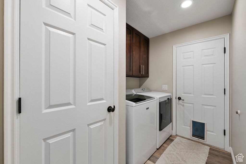 Washroom featuring washer and clothes dryer, cabinet space, light wood-style floors, baseboards, and recessed lighting