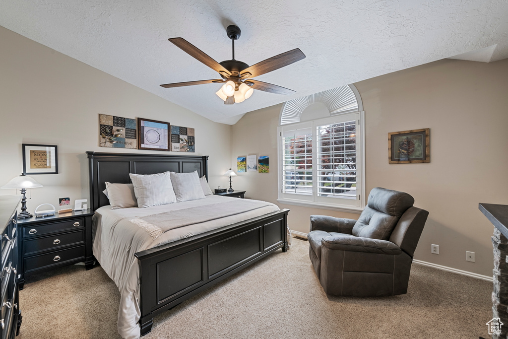 Bedroom featuring light colored carpet, a ceiling fan, a textured ceiling, lofted ceiling, and baseboards