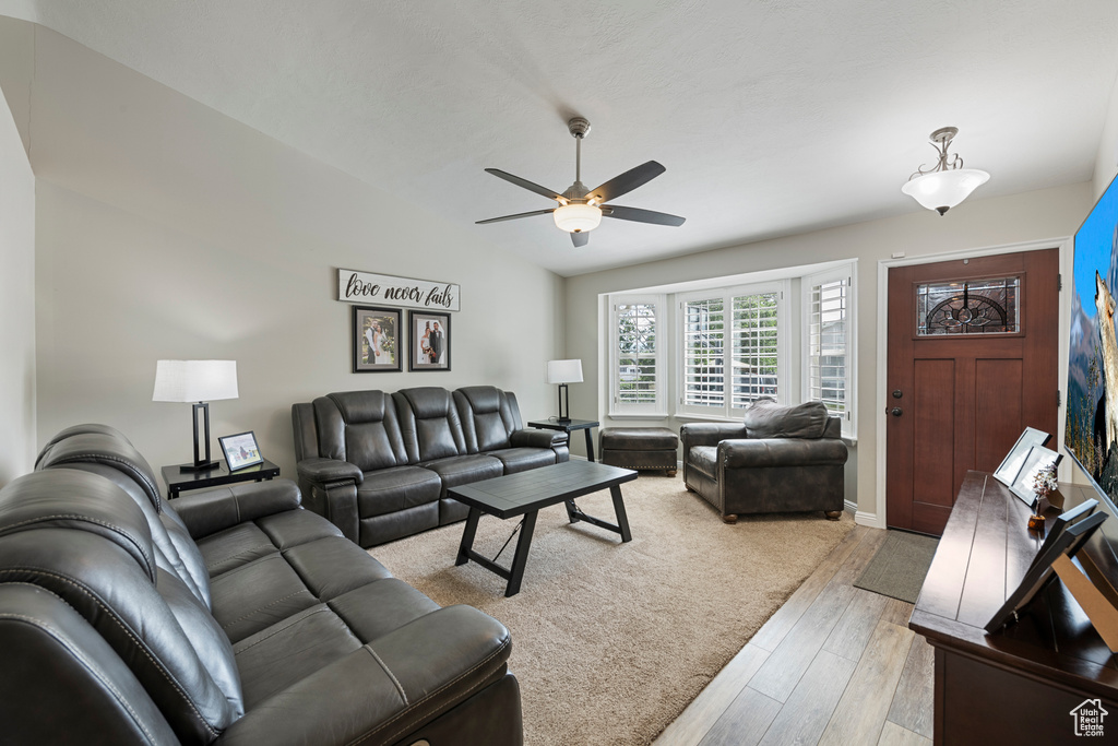Living area with a ceiling fan, light wood finished floors, and baseboards
