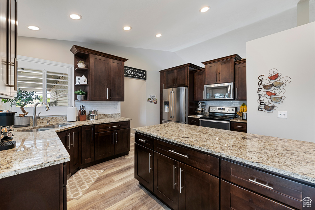 Kitchen featuring stainless steel appliances, a sink, tasteful backsplash, open shelves, and dark brown cabinets