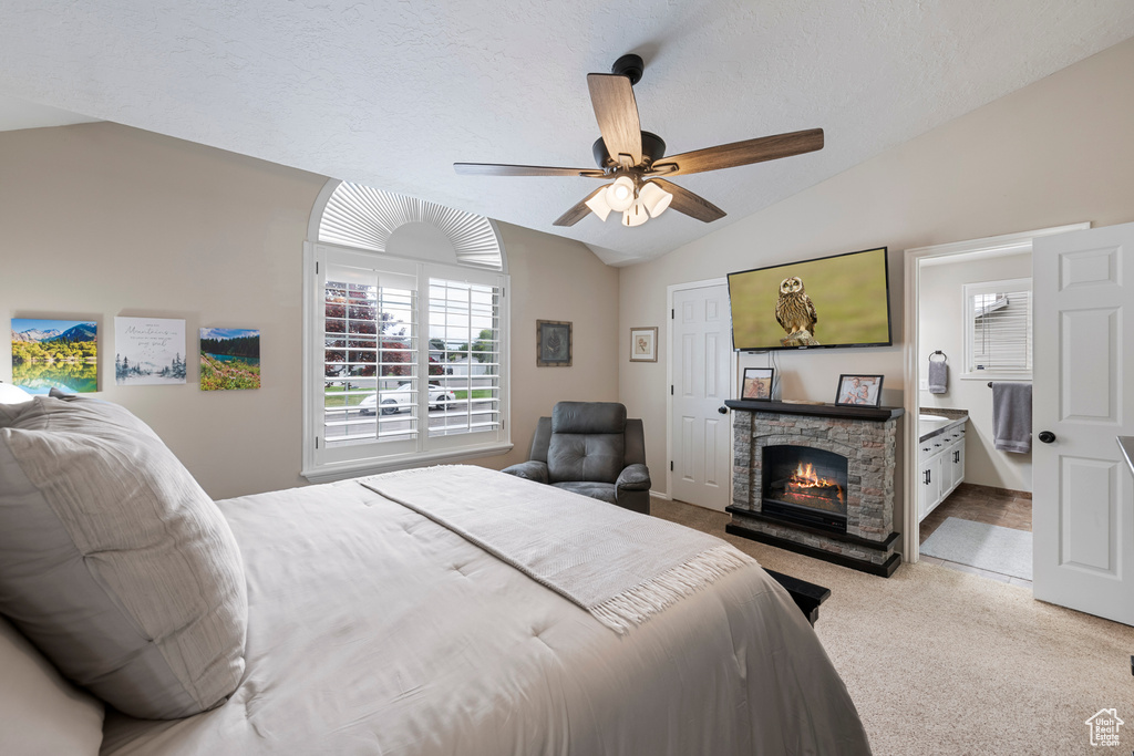 Bedroom with carpet flooring, vaulted ceiling, a fireplace, a ceiling fan, and ensuite bathroom