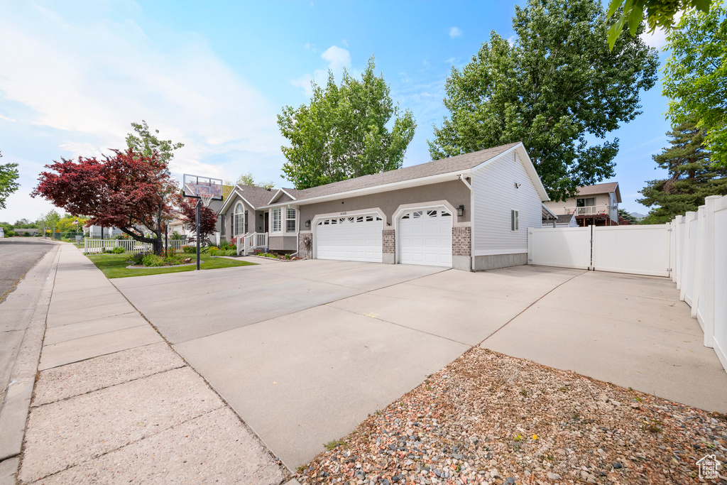 View of side of property with driveway, an attached garage, and a shingled roof