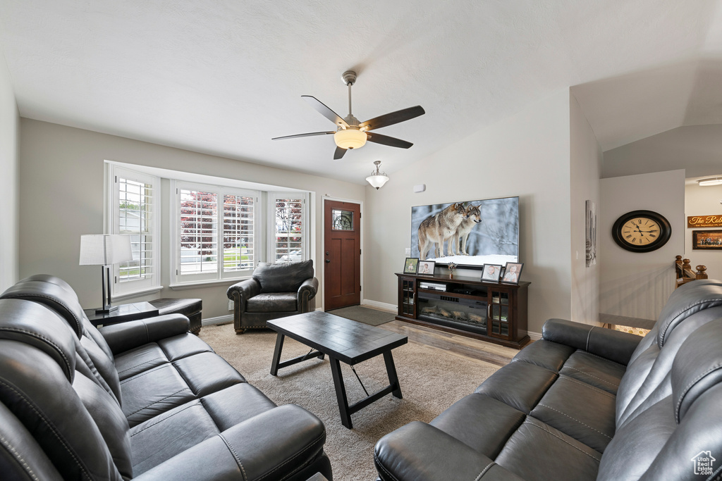 Living room featuring vaulted ceiling, ceiling fan, and baseboards