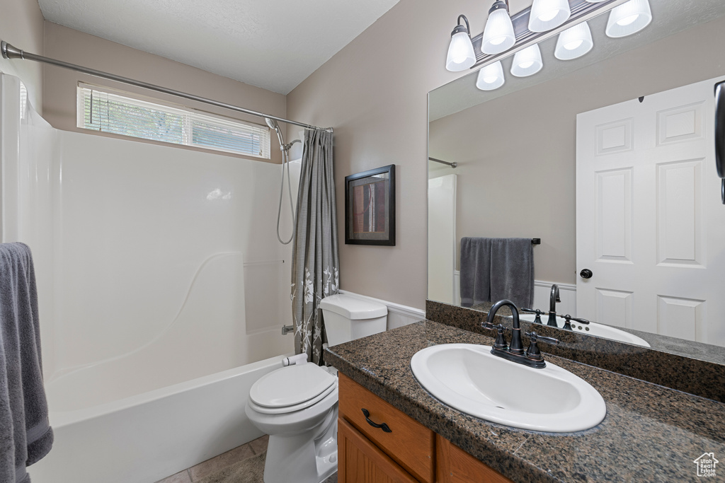 Full bathroom with shower / bath combo with shower curtain, vanity, and toilet