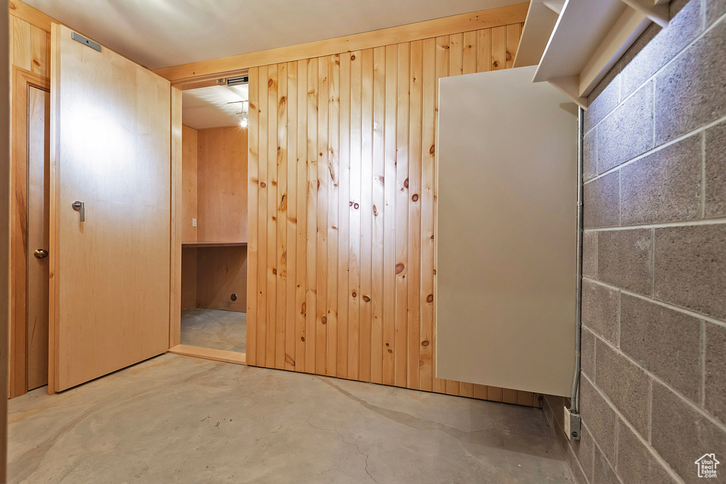 Unfurnished bedroom featuring unfinished concrete flooring and wooden walls