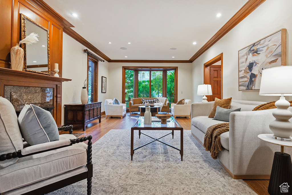 Living room featuring light wood finished floors, ornamental molding, recessed lighting, and a fireplace