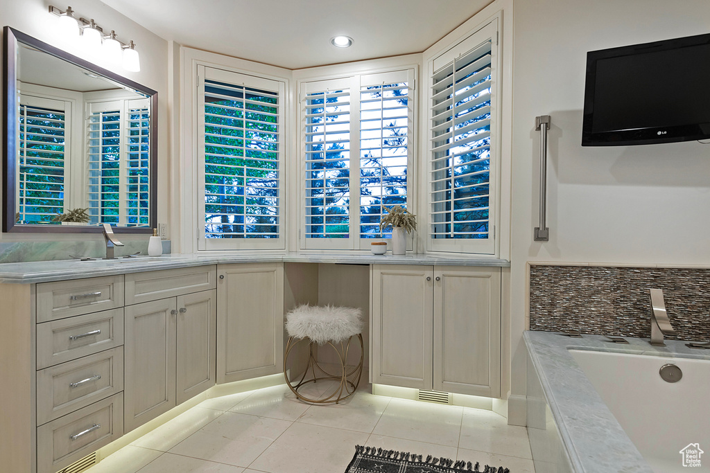 Bathroom featuring tile patterned flooring, a garden tub, and vanity