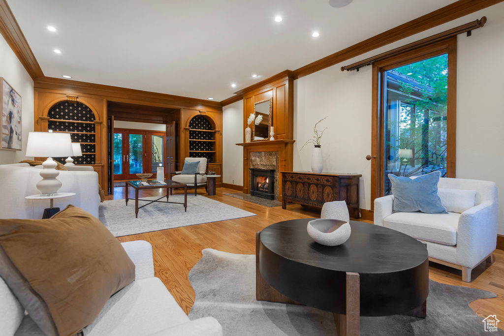 Living area featuring ornamental molding, built in features, light wood-style floors, recessed lighting, and a premium fireplace