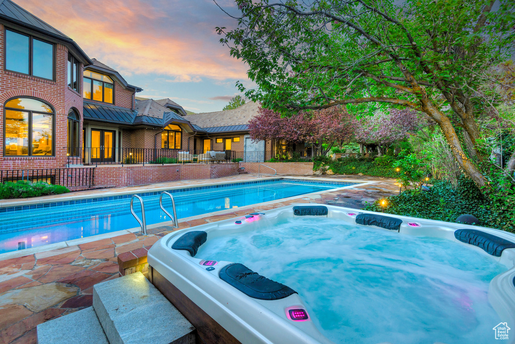 View of pool featuring a hot tub, a patio area, and french doors