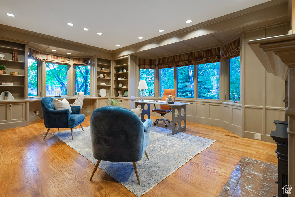 Office featuring crown molding, light wood-style flooring, recessed lighting, built in shelves, and a decorative wall