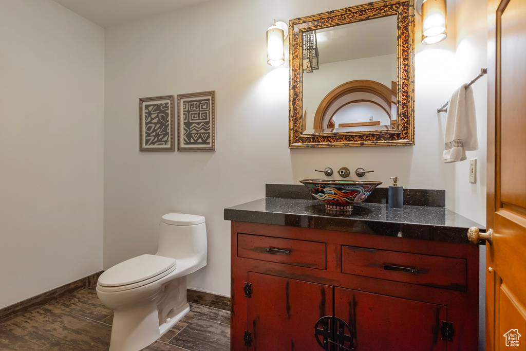 Half bath featuring vanity, toilet, and baseboards