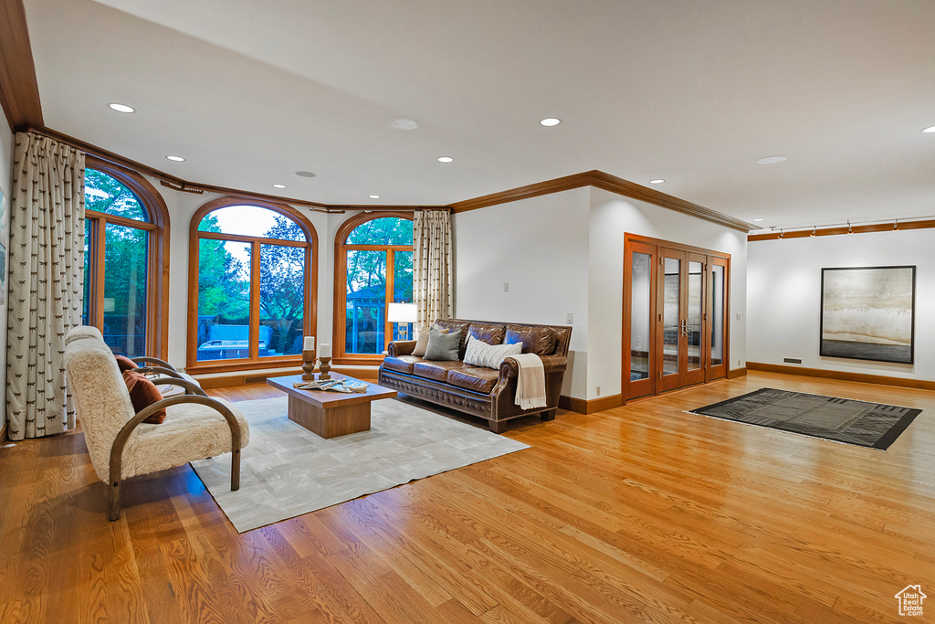 Living area featuring ornamental molding, light wood-type flooring, recessed lighting, baseboards, and french doors